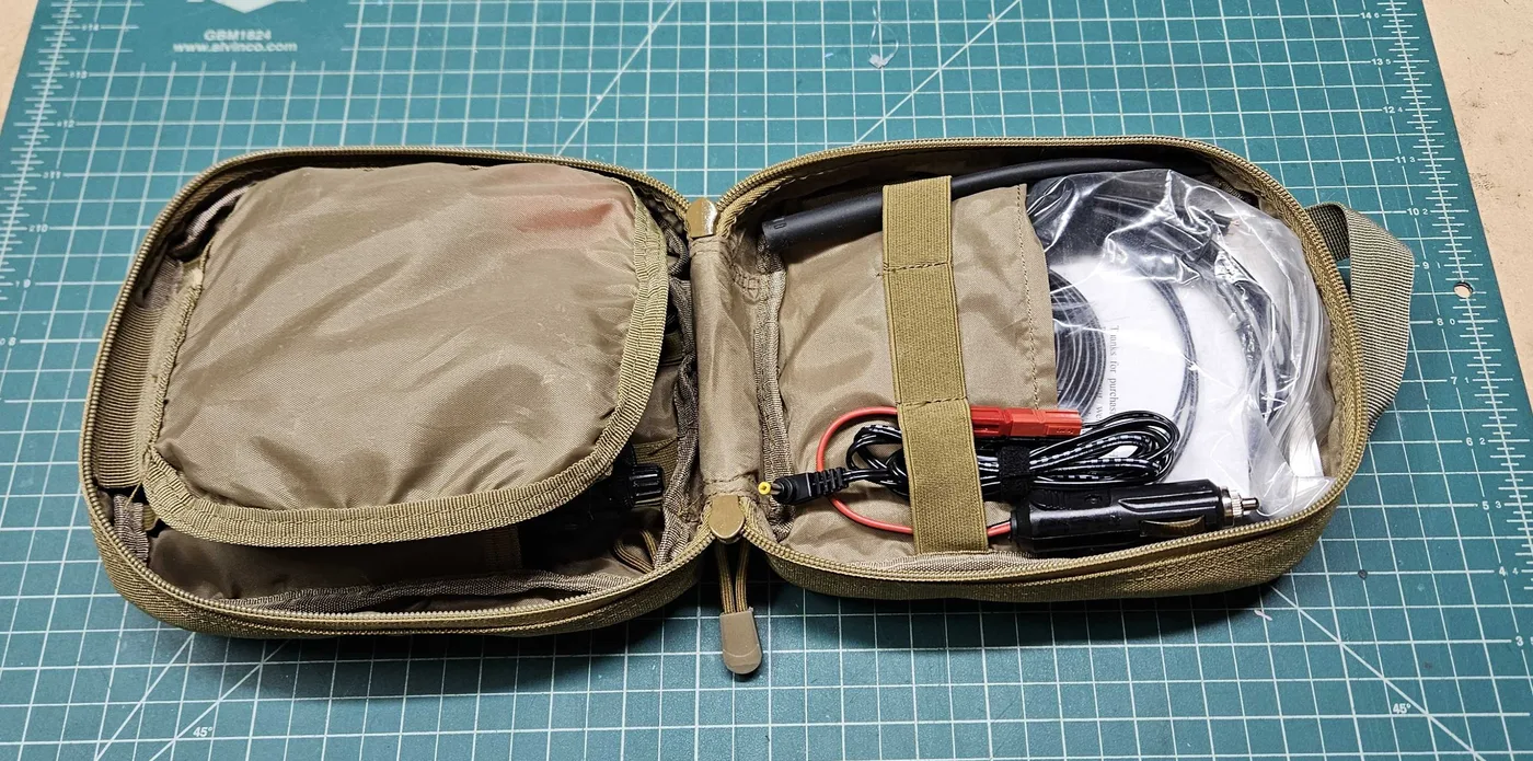 The pouch opened from the other side, showing a mesh pocket, chargers with alligator clips and a coil of cable in a clear bag