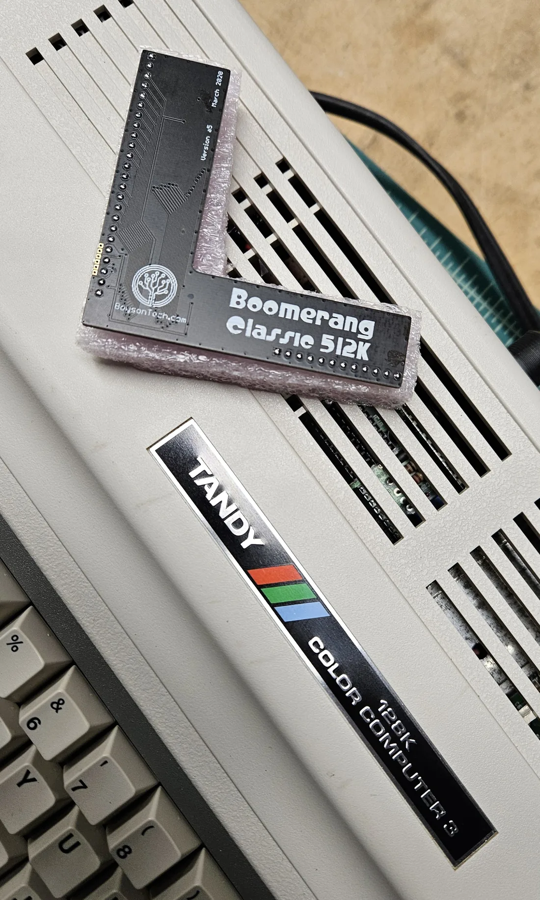 The L-shaped Boomerang Classic 512K memory board resting on top of the computer, next to the 128K Color Computer 3 badge