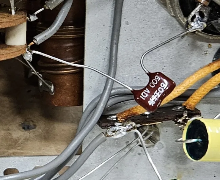 A small dark red mica capacitor soldered in between the band switch and a terminal strip